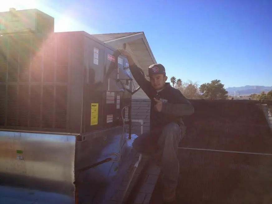 HVAC technician performing AC Tune-Up on a rooftop unit in Sylvester